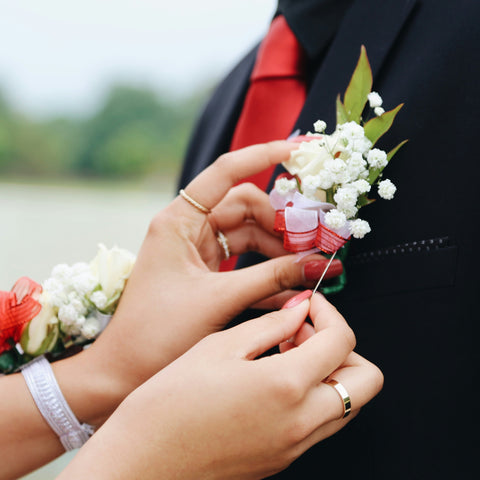 Woman pinning floral corsage on a man's lapel 